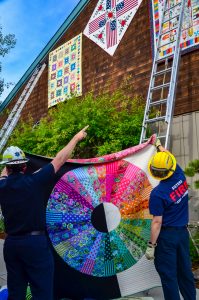 The volunteer firemen strategize hanging up the quilts