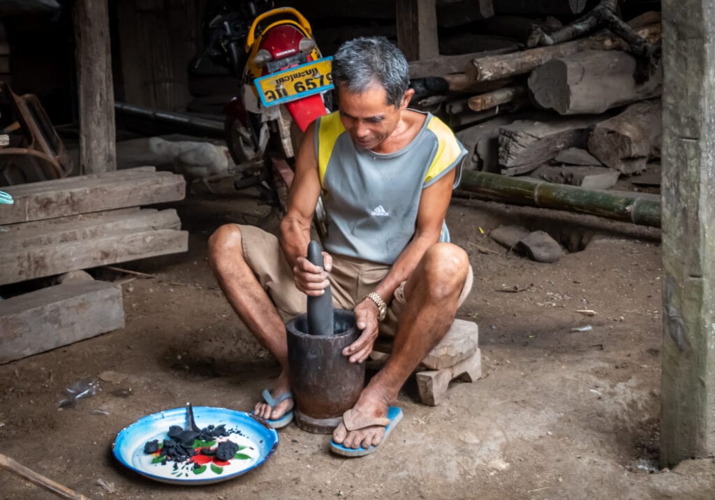 a villager grinds gunpowder in Laos