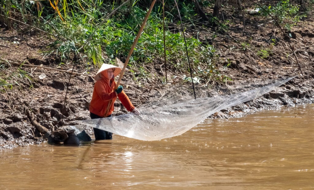 a woman fishing from the bank in Laos