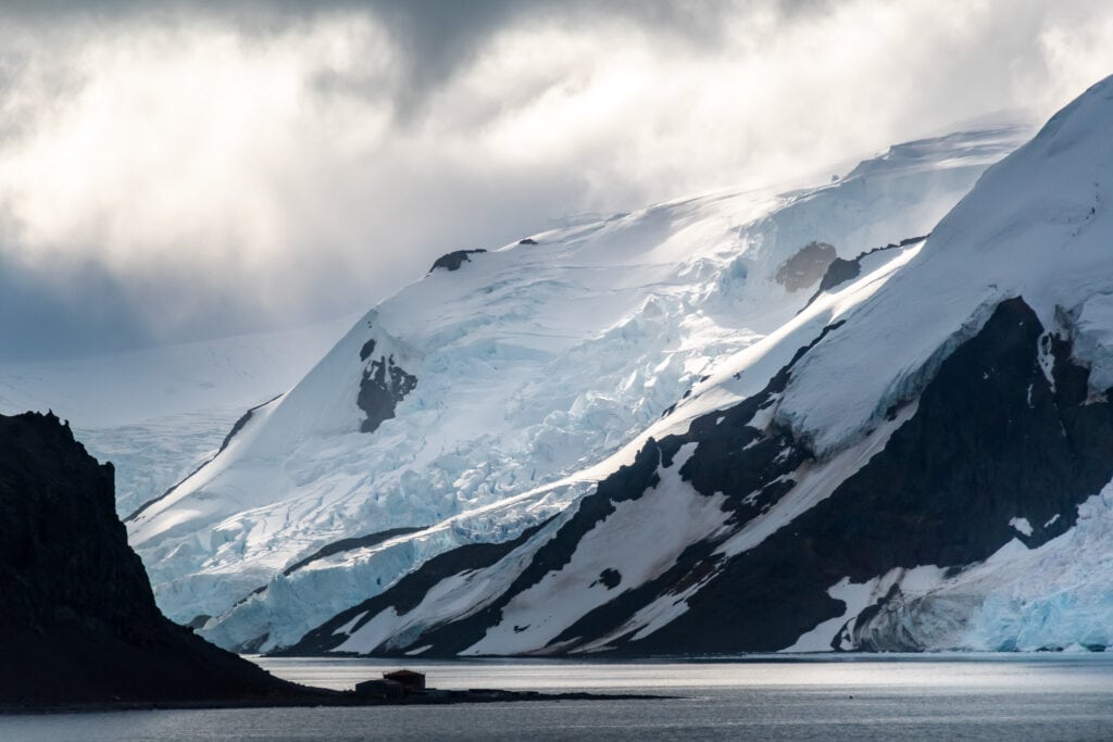 A research station is dwarfed by the surrounding mountains and glaciers