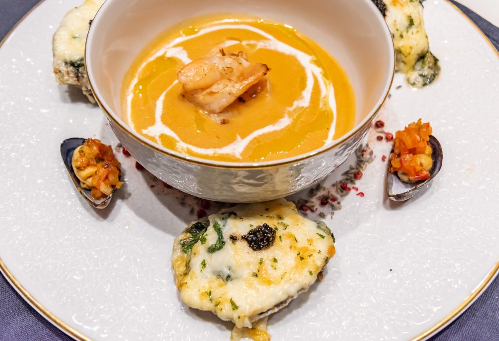 Seafood bisque with brandy cream served with oysters Rockefeller