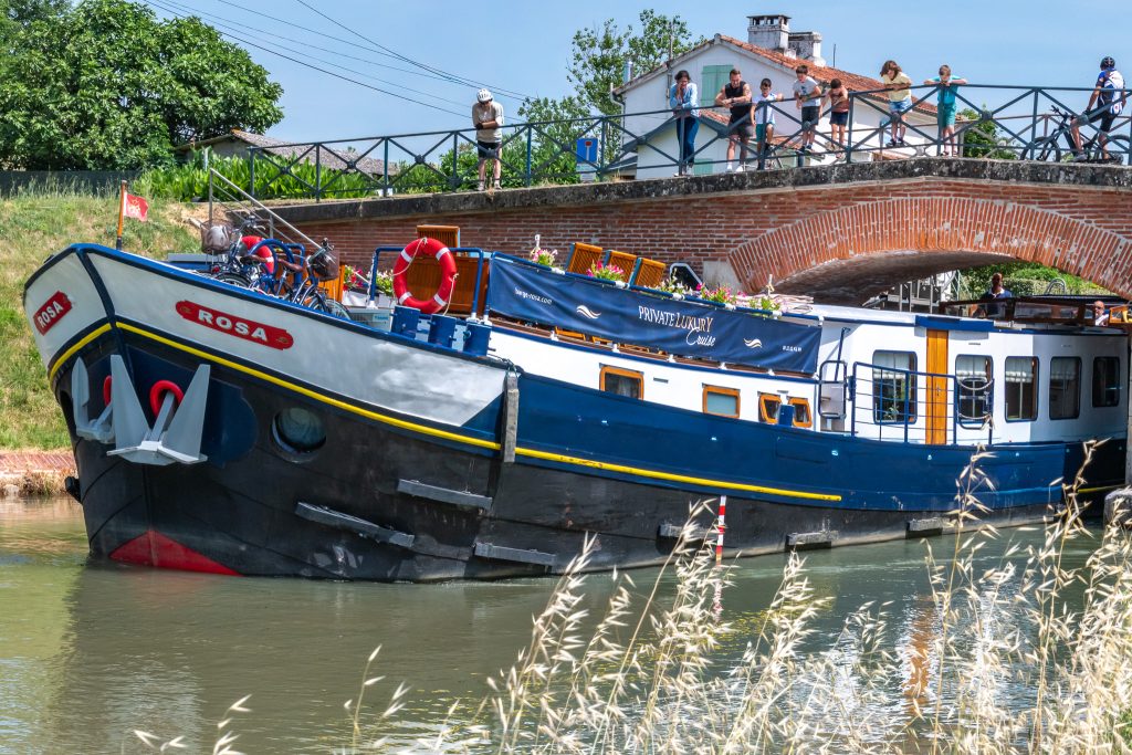 Locals admire the Rosa as she passes under a historic bridge